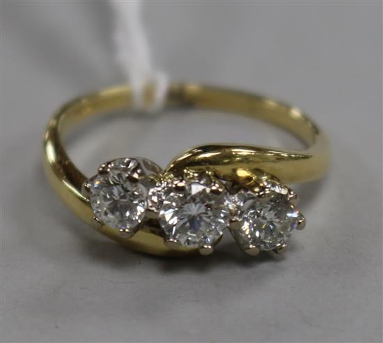 A modern 18ct gold and three stone diamond crossover ring, size R.